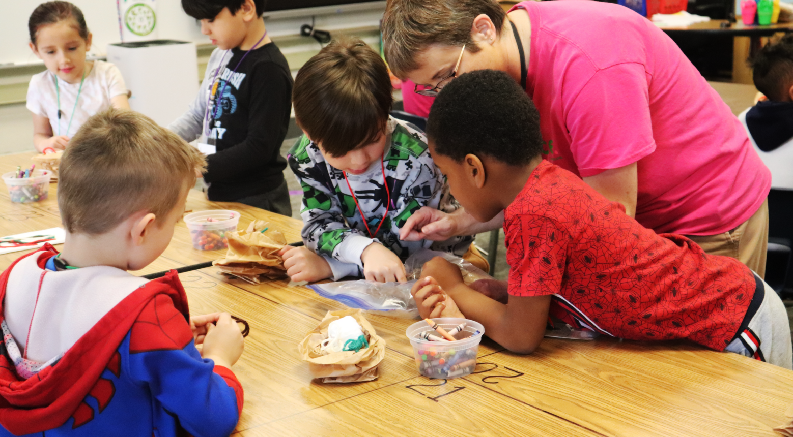 Students working with teacher to building replica bird's nest.